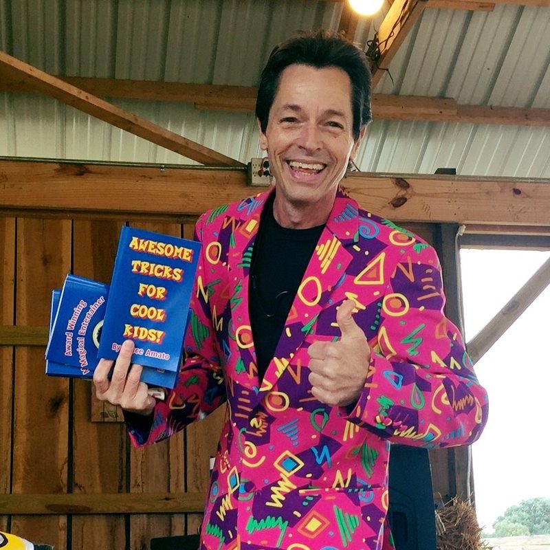Magician Bruce Amato holding his Awesome Tricks For Cool Kids books at Shuckle’s Corn Maze